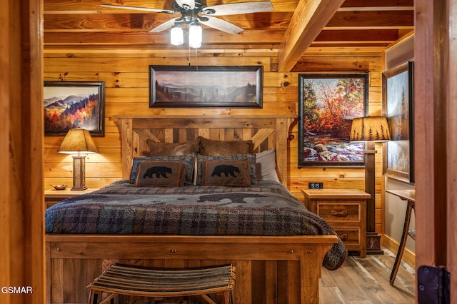 bedroom with wooden walls, light wood-style flooring, and beamed ceiling