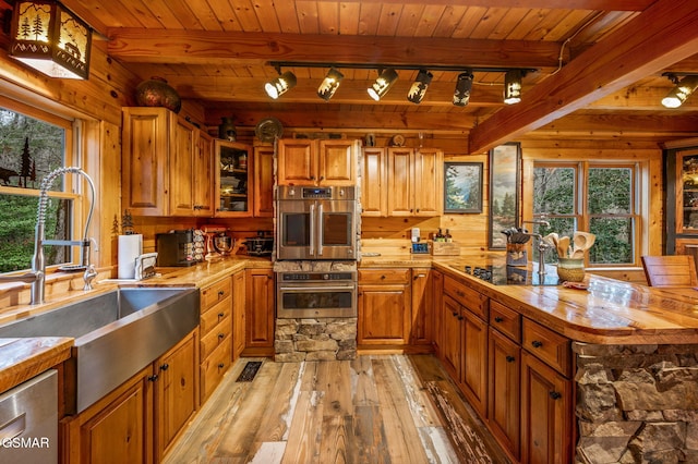 kitchen with a sink, stainless steel appliances, a wealth of natural light, and brown cabinetry