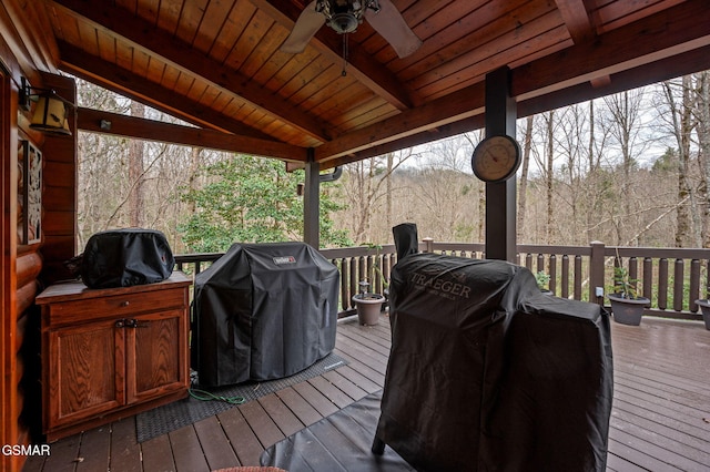 deck with area for grilling, a ceiling fan, and a forest view