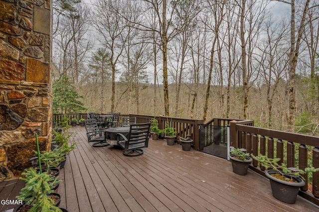 deck featuring outdoor dining area and a wooded view