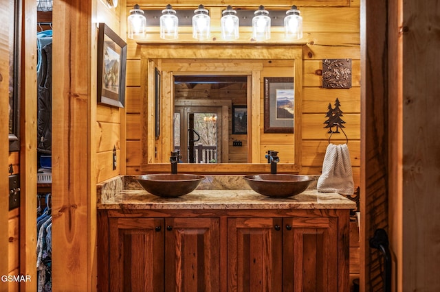 full bathroom featuring a sink, wood walls, and double vanity