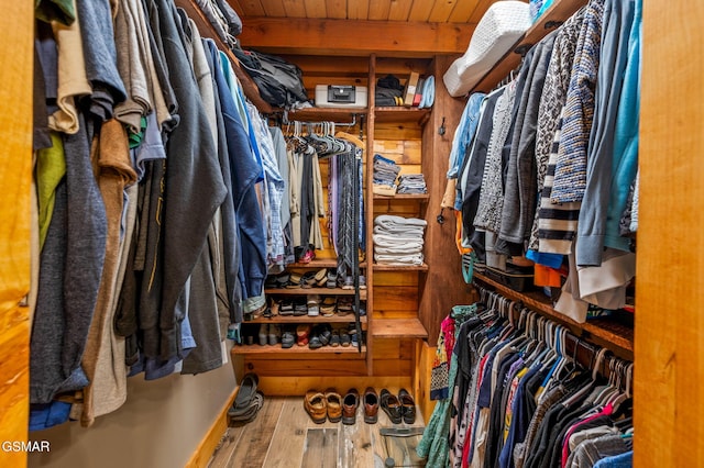 spacious closet featuring beam ceiling and wood finished floors