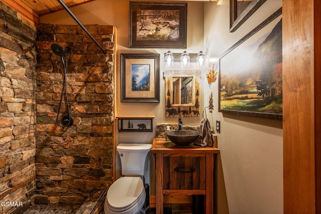 bathroom featuring a tile shower, toilet, and vanity