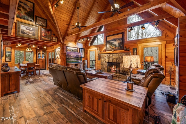 living area with lofted ceiling with beams, wooden ceiling, wood walls, a fireplace, and dark wood-style flooring