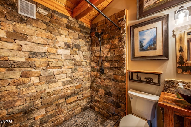 bathroom featuring visible vents, toilet, wood ceiling, lofted ceiling with beams, and tiled shower