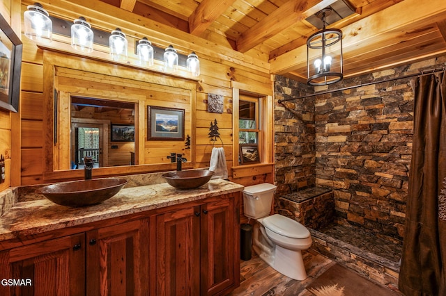 bathroom with beamed ceiling, toilet, double vanity, a tile shower, and a sink