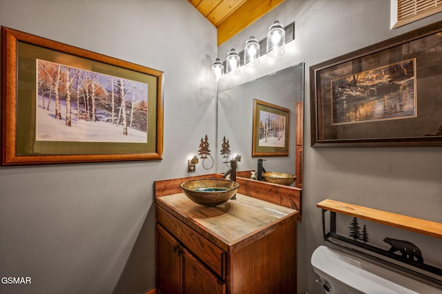 bathroom with vanity, vaulted ceiling, and toilet