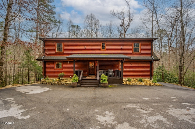 log home with a porch, driveway, and roof with shingles