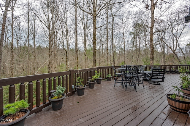 deck featuring outdoor dining area and a wooded view