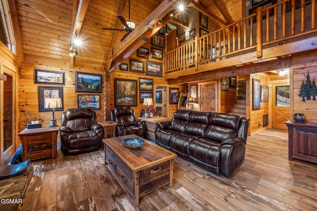 living area with hardwood / wood-style floors, wooden walls, a ceiling fan, vaulted ceiling with beams, and wooden ceiling