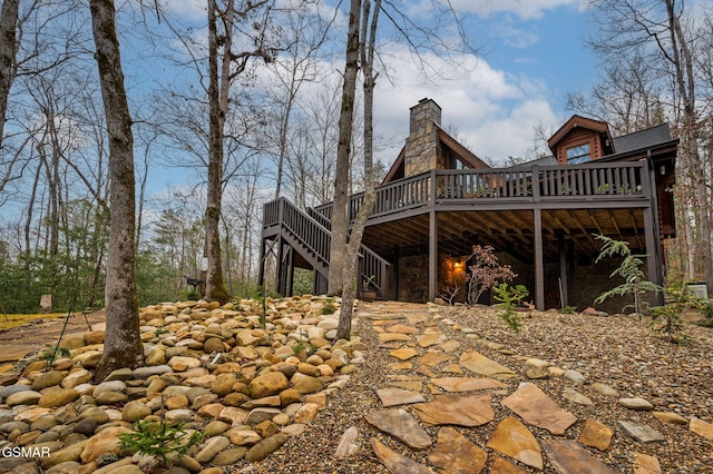 view of home's exterior with a chimney, stairway, and a wooden deck