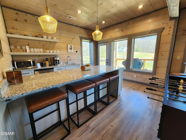 kitchen featuring visible vents, wood ceiling, stainless steel microwave, wood finished floors, and a sink