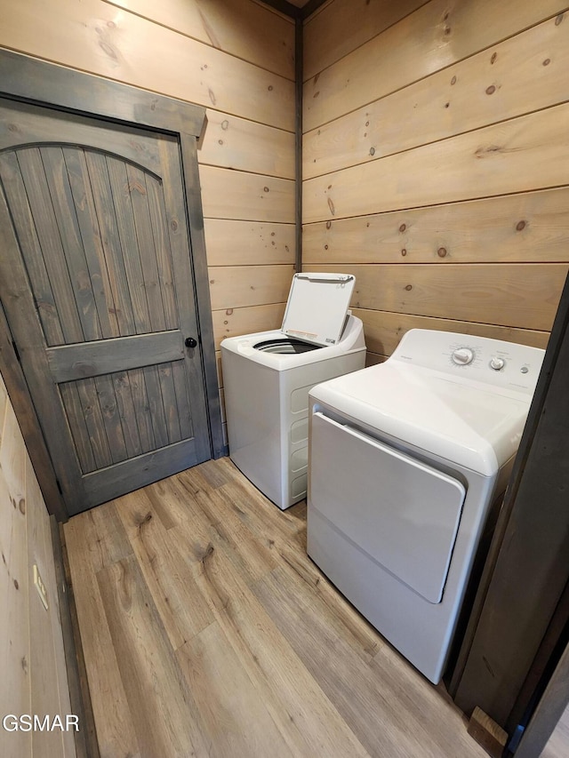 washroom featuring laundry area, wooden walls, light wood finished floors, and washer and dryer