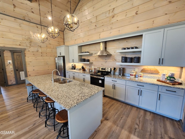 kitchen with a breakfast bar area, open shelves, appliances with stainless steel finishes, a sink, and wood finished floors