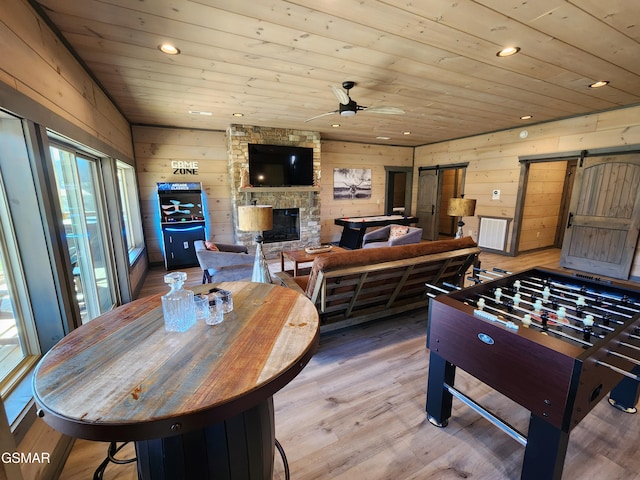 playroom featuring a barn door, recessed lighting, wood walls, wood ceiling, and light wood-type flooring