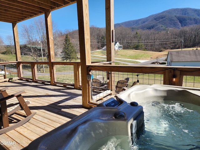 wooden deck with a hot tub and a mountain view