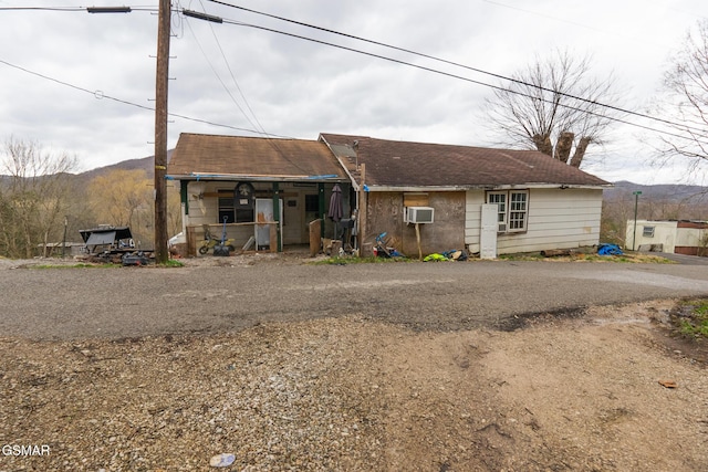 rear view of property with covered porch, a mountain view, and an AC wall unit