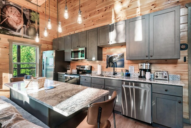 1013 Silver Poplar Ln, Sevierville, TN 37876 - kitchen with appliances with stainless steel finishes, a sink, wooden walls, a kitchen island, and a breakfast bar area