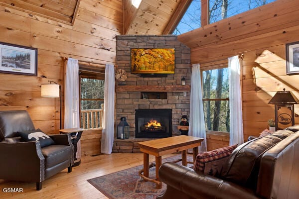 living area with wood walls, a fireplace, high vaulted ceiling, and wood finished floors