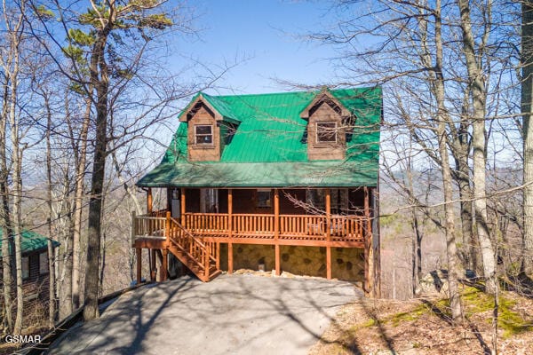 view of front of house featuring metal roof, a porch, and stone siding