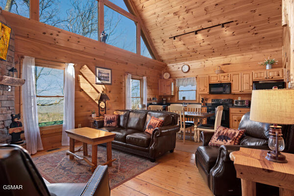 living room featuring wood ceiling, high vaulted ceiling, wood walls, and light wood-style flooring