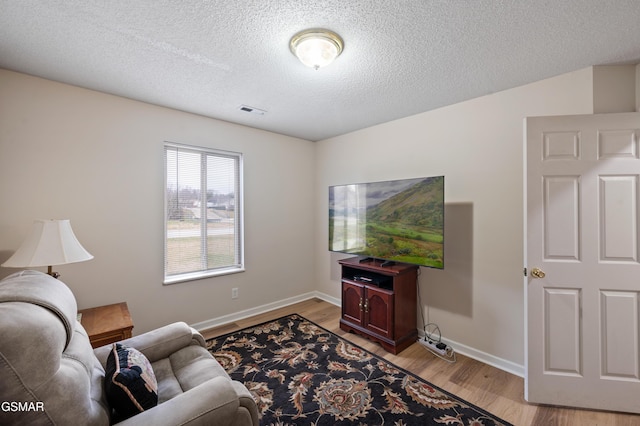 living room with light hardwood / wood-style floors and a textured ceiling