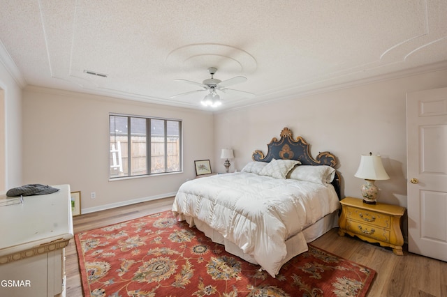 bedroom with a textured ceiling, ceiling fan, wood-type flooring, and crown molding