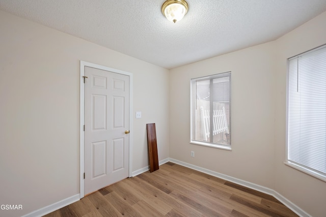 unfurnished room with a healthy amount of sunlight, a textured ceiling, and light wood-type flooring