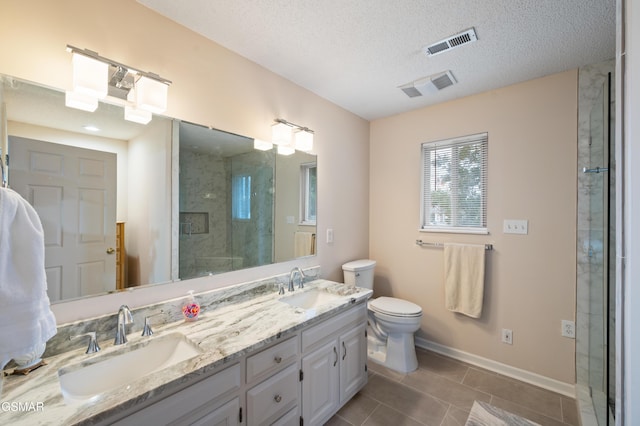 bathroom featuring vanity, a textured ceiling, a shower with door, tile patterned flooring, and toilet