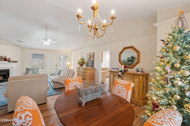 dining room with light hardwood / wood-style flooring, ceiling fan with notable chandelier, and vaulted ceiling