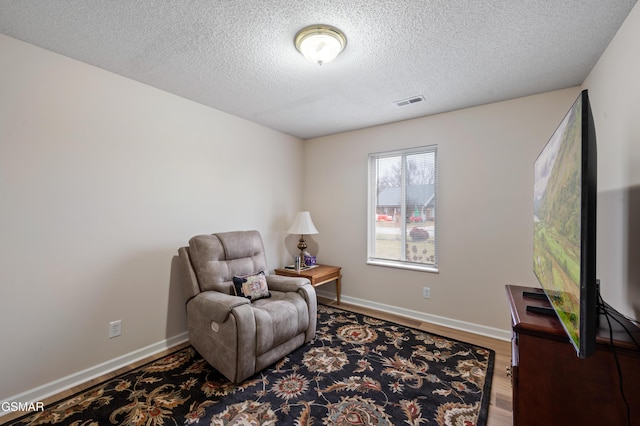 living area with hardwood / wood-style floors and a textured ceiling