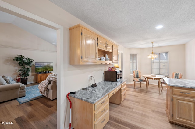 kitchen featuring light stone counters, light brown cabinets, hanging light fixtures, and light wood-type flooring