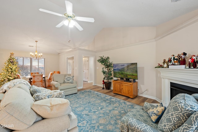 living room featuring lofted ceiling, crown molding, light wood-type flooring, and ceiling fan with notable chandelier