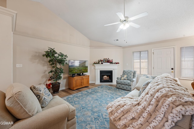 living room with ceiling fan, light wood-type flooring, crown molding, and lofted ceiling