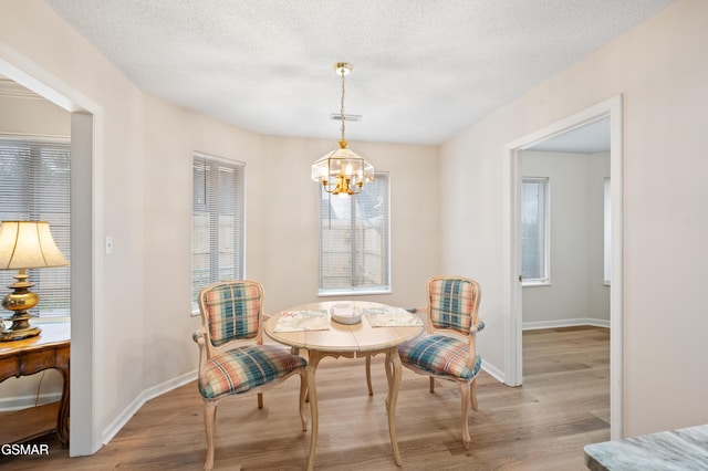 living area featuring a notable chandelier, light hardwood / wood-style floors, and a textured ceiling