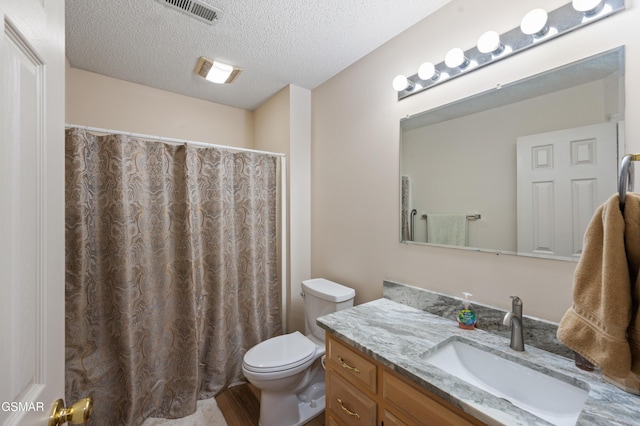 bathroom with walk in shower, vanity, a textured ceiling, hardwood / wood-style floors, and toilet