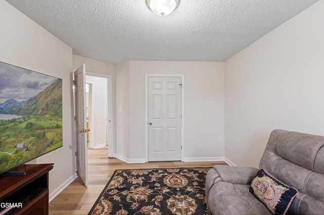 living area with a textured ceiling and light hardwood / wood-style flooring