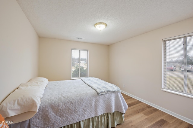 bedroom featuring light hardwood / wood-style floors and a textured ceiling