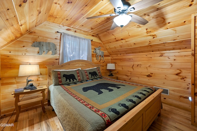 bedroom featuring lofted ceiling, wooden ceiling, wood walls, wood-type flooring, and a ceiling fan