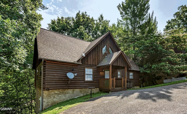 view of front of house with a shingled roof and log exterior