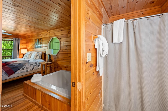 ensuite bathroom with wood ceiling, wooden walls, wood finished floors, a tub to relax in, and a shower with curtain