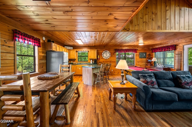 living room with wood ceiling, wooden walls, light wood finished floors, and plenty of natural light