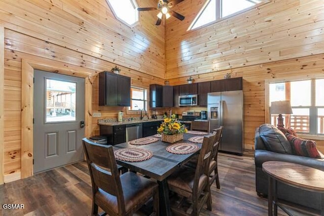 dining space with hardwood / wood-style floors, high vaulted ceiling, ceiling fan, and wood walls