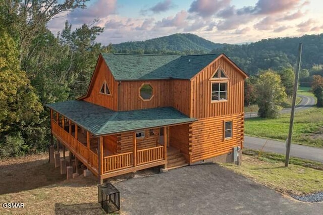 outdoor structure at dusk with a mountain view, a porch, and a lawn