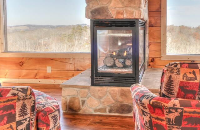 interior details with hardwood / wood-style floors, wood walls, and a stone fireplace