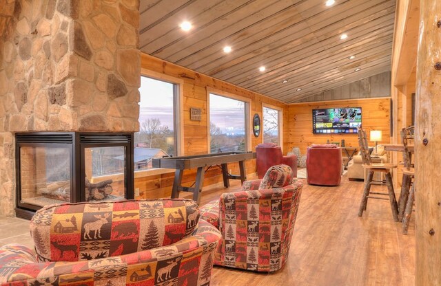 living room with wooden walls, wooden ceiling, a fireplace, hardwood / wood-style floors, and lofted ceiling