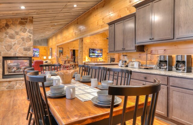 dining area with bar area, wood walls, wood ceiling, and light hardwood / wood-style floors