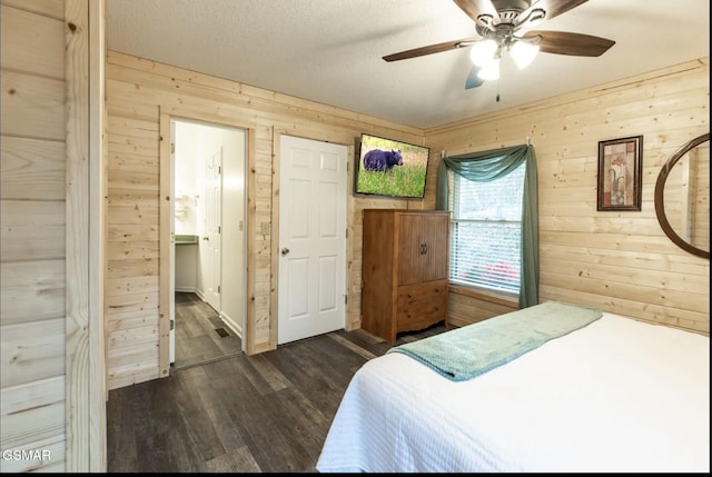 bedroom featuring a textured ceiling, wooden walls, ceiling fan, and dark wood-type flooring