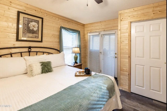 bedroom featuring ceiling fan, wood walls, and dark hardwood / wood-style flooring