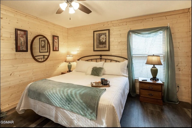 bedroom featuring ceiling fan, dark wood-type flooring, and wood walls